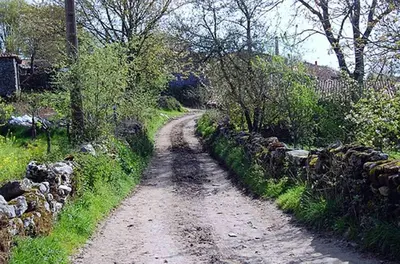 a dirt road next to a stone wall at Stone Cottage La COMPOSTELANA in Curtis