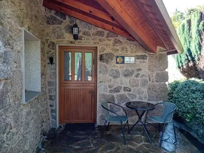 a stone house with a table and chairs and a door at Stone Cottage La COMPOSTELANA in Curtis