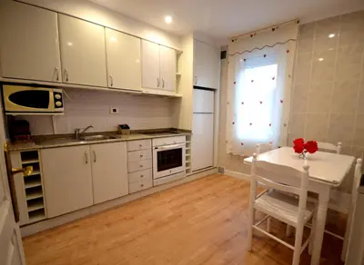 a kitchen with white cabinets and a table and a window at Casa Jardín in Monforte de Lemos
