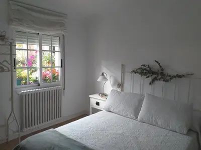 a white bedroom with a bed and a window at Casa Jardín in Monforte de Lemos