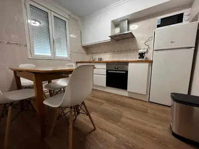 a kitchen with a wooden table and white appliances at Castiñeiras Street in Sarria