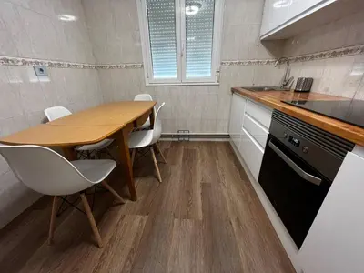 a small kitchen with a wooden table and white chairs at Castiñeiras Street in Sarria