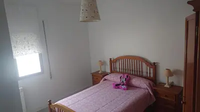a bedroom with a bed with a purple bedspread and a pink stuffed animal at Foz Playas in Foz