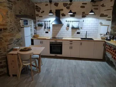 a kitchen with white cabinets and a table and a stove at A curuxa casa rural in El Mazo