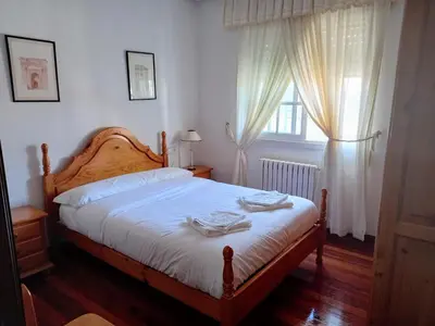a bedroom with a bed with white sheets and a window at Ático Pilos in Castro Caldelas