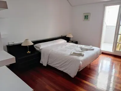a bedroom with a white bed and a wooden floor at Ático Pilos in Castro Caldelas