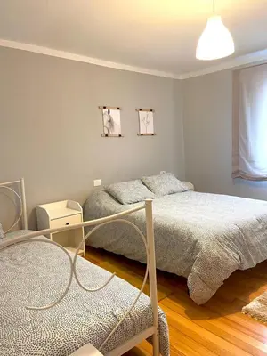 a bedroom with two beds and a chair in it at Casa Concha do Caserón do Viaxeiro in Mondoñedo