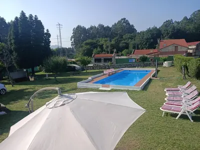 a white umbrella in front of a swimming pool at LA CAMELIA in Pontevedra