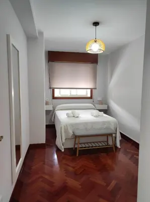 a bedroom with a white bed and a wooden floor at Apartamento a 5 minutos del casco histórico in Viveiro
