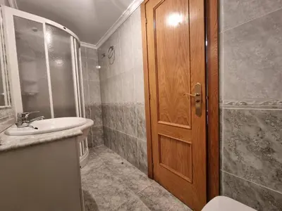 a bathroom with a sink and a wooden door at Apartamento en Playa Rapadoira in Foz