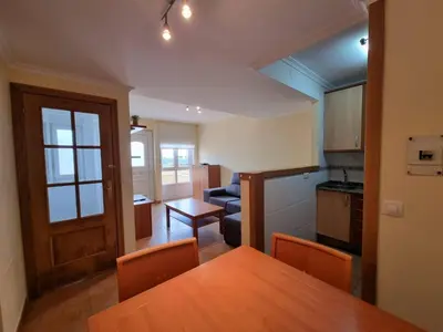 a kitchen and living room with a wooden table and chairs at Apartamento en Playa Rapadoira in Foz