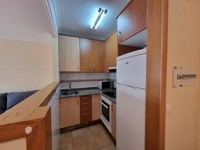 a kitchen with wooden cabinets and a white refrigerator at Apartamento en Playa Rapadoira in Foz