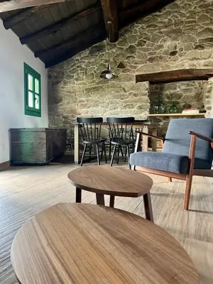 a room with chairs and tables and a stone wall at A Parada House by Kev in Parada del Sil