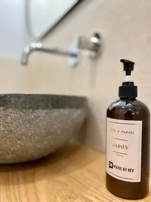 a bottle of soap sitting next to a bathroom sink at A Parada House by Kev in Parada del Sil