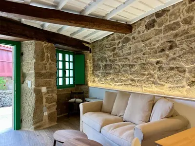 a living room with a couch and a stone wall at A Parada House by Kev in Parada del Sil