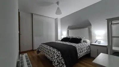 a bedroom with a bed with a black and white comforter at Piso puerto Foz in Foz