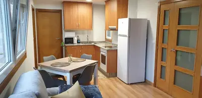 a kitchen with a table and a white refrigerator at Piso puerto Foz in Foz