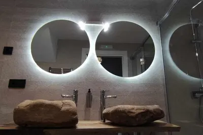 a bathroom with two mirrors and a sink with a large rock at Precioso Apartamento 2 Hab. con Bañera Hidromasaje in O Barco de Valdeorras