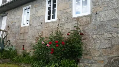 a stone building with red roses in front of it at Casa de Alicia Pontevedra Moraña Rías Baixas Casa Entera VT-PO-OOOO32 in Moraña