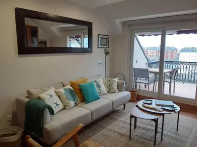 a living room with a couch and a table at Atico con terraza y piscina comunitaria in Ribadeo