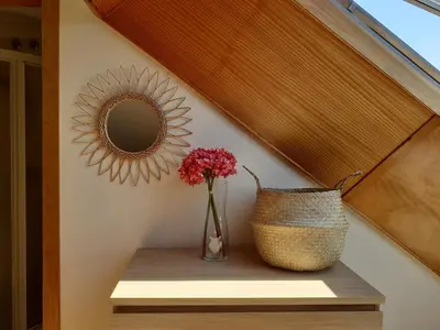 a vase of flowers on a shelf with a mirror at Atico con terraza y piscina comunitaria in Ribadeo