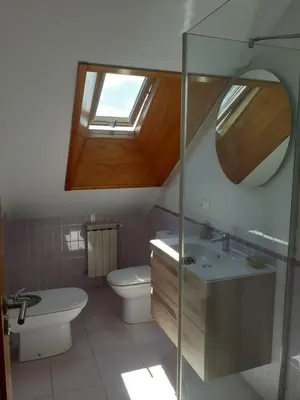 a bathroom with a toilet and a sink and a window at Atico con terraza y piscina comunitaria in Ribadeo