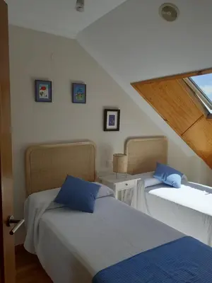 a bedroom with two beds and a window at Atico con terraza y piscina comunitaria in Ribadeo