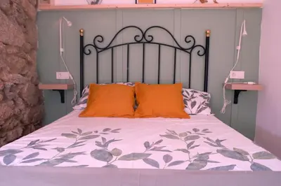 a bed with an iron headboard and orange pillows at A casa da Penela in Sas de Penelas