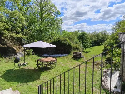 a patio with an umbrella and a table and a grill at A casa da Penela in Sas de Penelas