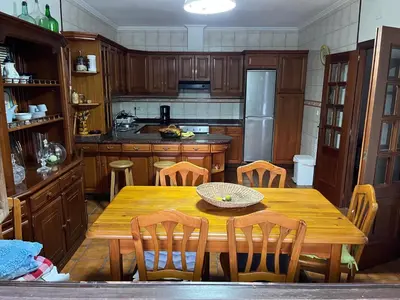 a kitchen with a wooden table and wooden chairs at Casa Santa Ana in Tourón