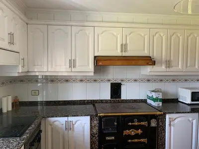 a kitchen with white cabinets and a stove top oven at Casa ferreiro in Ribadeo