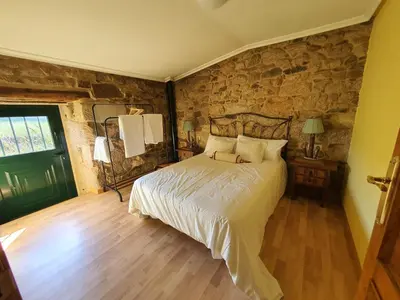 a bedroom with a bed and a stone wall at A Palleira de Aguil in Castro Caldelas