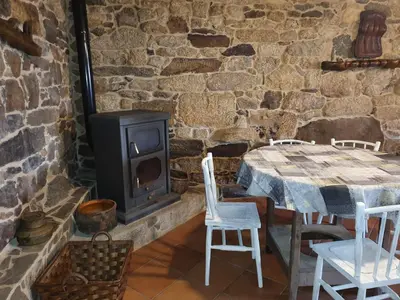 a stone room with a table and a stove at A Palleira de Aguil in Castro Caldelas