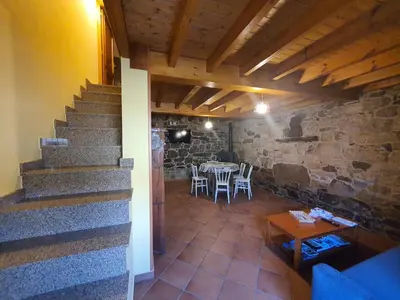 a room with a staircase and a table and chairs at A Palleira de Aguil in Castro Caldelas