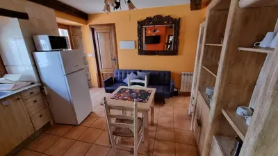 a small kitchen with a table and a refrigerator at Casa jardin Mariana in Lubián