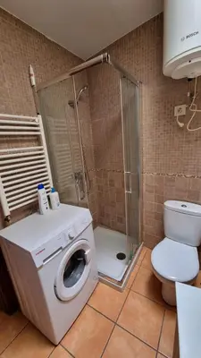a bathroom with a washing machine and a toilet at Casa jardin Mariana in Lubián