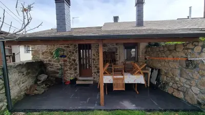 a stone house with a patio and a stone wall at Casa jardin Mariana in Lubián