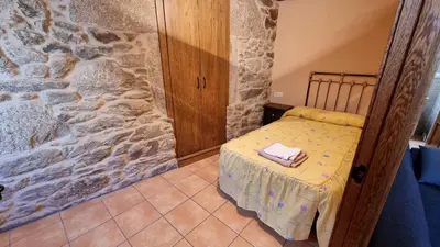 a small bed in a room with a stone wall at Casa jardin Mariana in Lubián