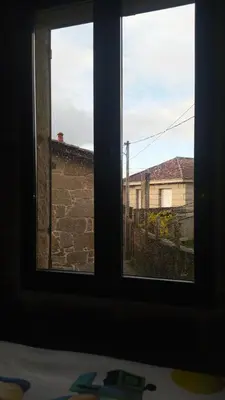 two windows in a room looking out at a building at Casa Amil da Vilaboa, Allariz in Allariz