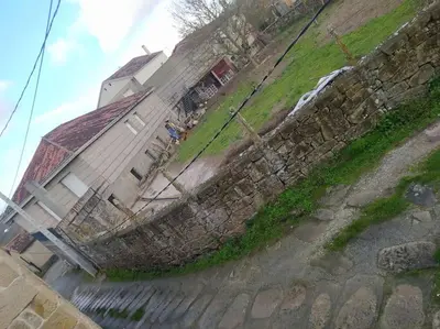 a stone wall next to a house with a fence at Casa Amil da Vilaboa, Allariz in Allariz