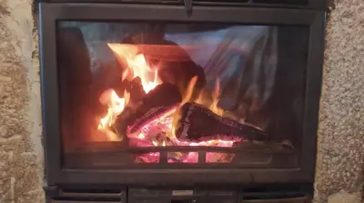 a person is sitting in a fire in a fireplace at Casa Amil da Vilaboa, Allariz in Allariz