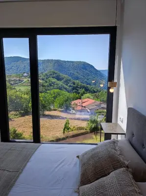a bedroom with a bed and a large window at Cabañas Alcobas do Sil Ecoturismo in Parada del Sil