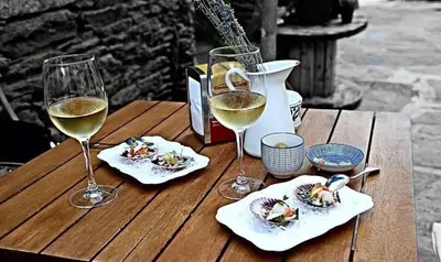 a wooden table with two glasses of white wine at Pazo de Bendoiro in Bendoiro