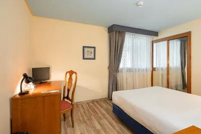 a hotel room with a bed and a desk with a computer at Hotel Alda Lalín in Lalín