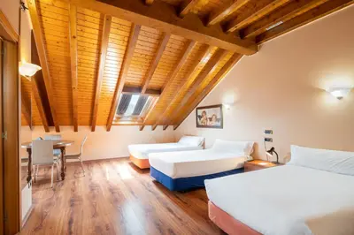 a hotel room with two beds and a table at Hotel Alda Lalín in Lalín
