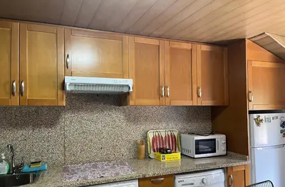 a kitchen with wooden cabinets and a white microwave at Carballo Alenza,2 in Castro Caldelas
