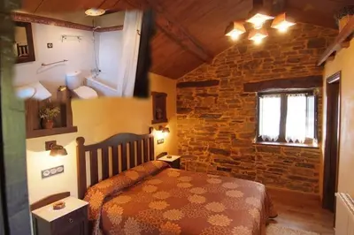 a bedroom with a bed and a stone wall at Pajar in Braña