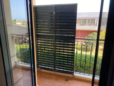 a sliding glass door with blinds on a balcony at Barreiros Playa Altar in Barreiros