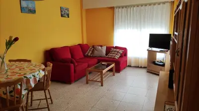 a living room with a red couch and a table at Amplio piso en Pontedeume in Puentedeume