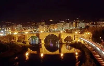 a bridge over a river with a city at night at Castelodobispo - Ourense in Sobrado del Obispo